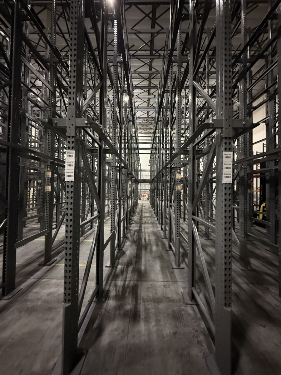Lane between drive-in rack rows showing labeled deep-storage pallet positions